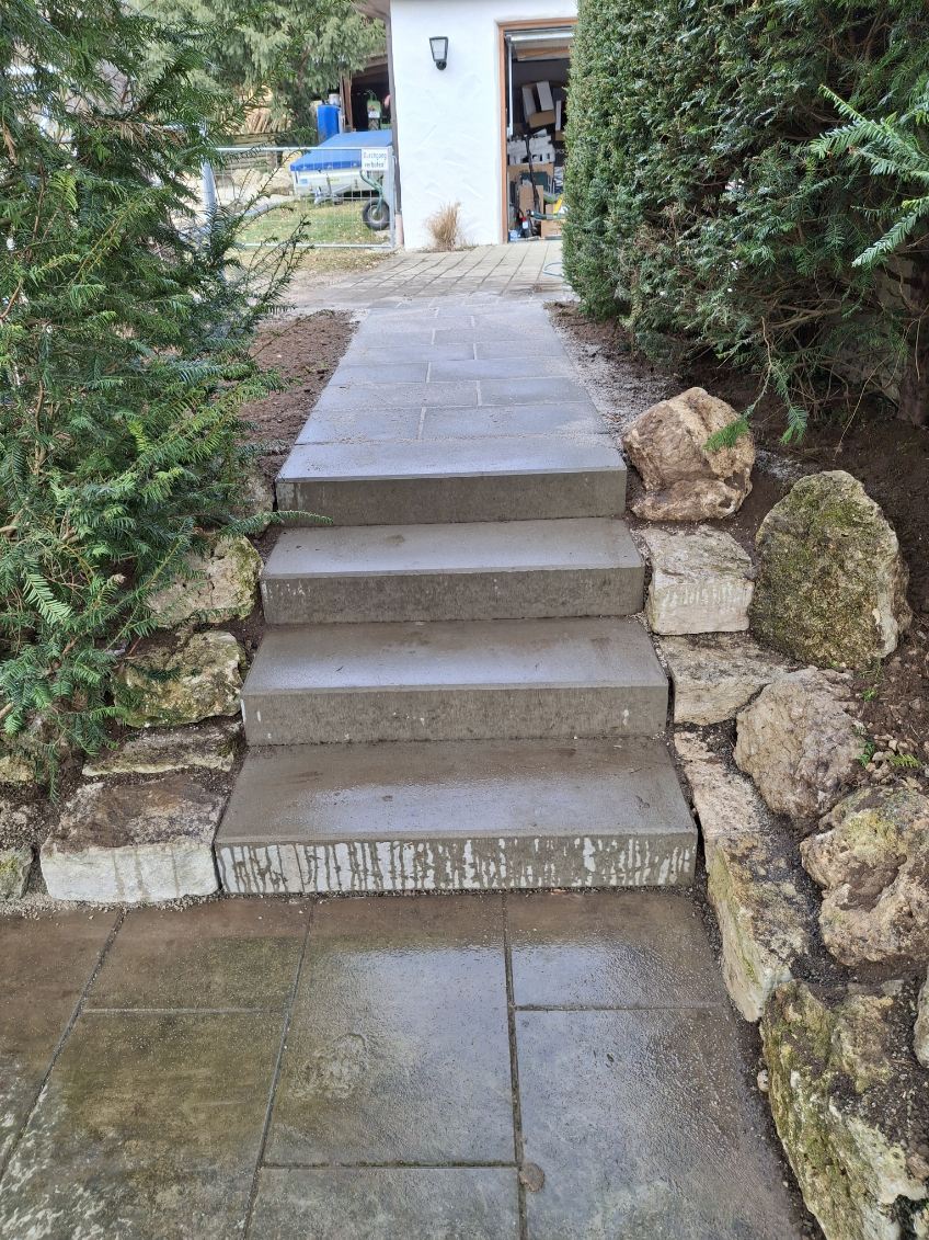 Eingangsbereich mit Sichtbetonstufen und Natursteinfassung